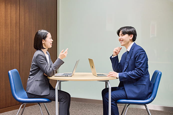 テーブルに向き合って打ち合わせを行う2名の社員