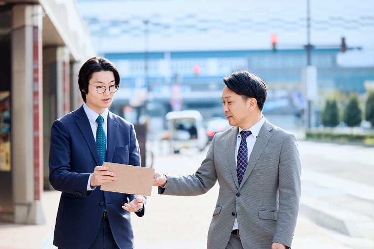 街中を歩きながら会話をする男性社員