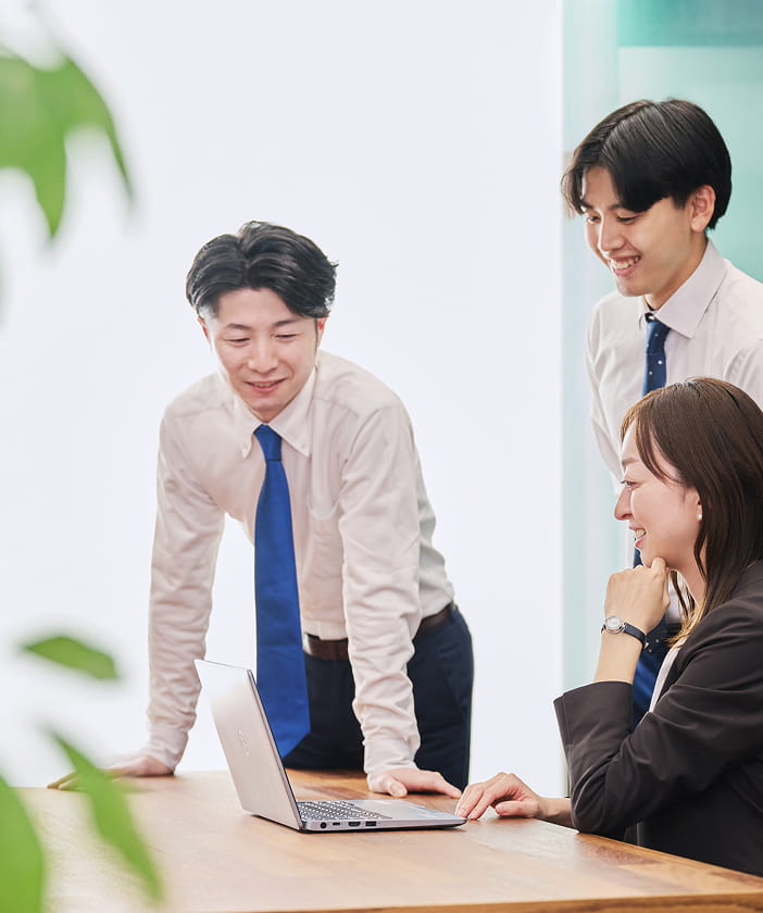 パソコンの画面を見ながら会話をする社員たち